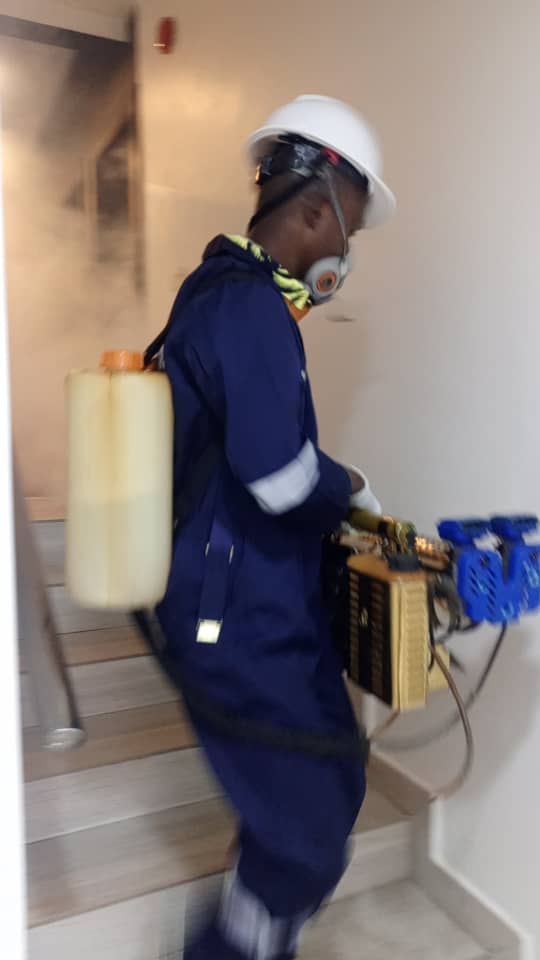 Technician fogging a stairwell in a multi-storey Abuja building
